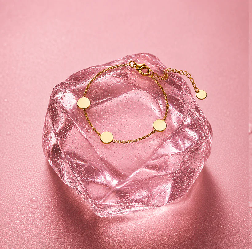 Delicate gold anklet arranged on a pink crystal
