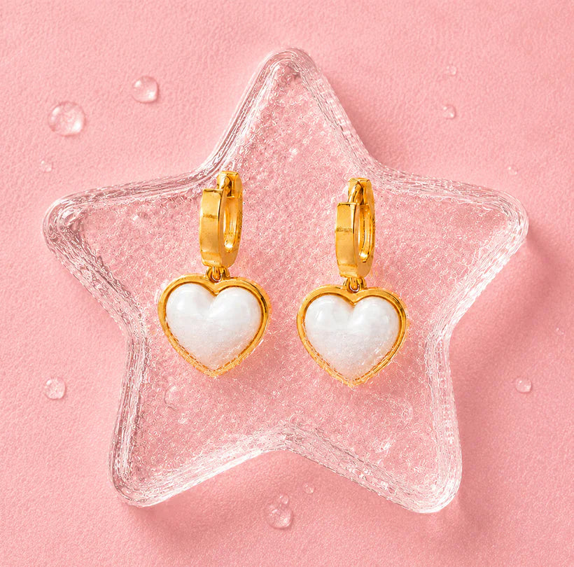 Gold heart earrings displayed on a pink crystal star