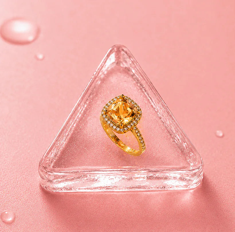 Gold crystal ring displayed on pink glass