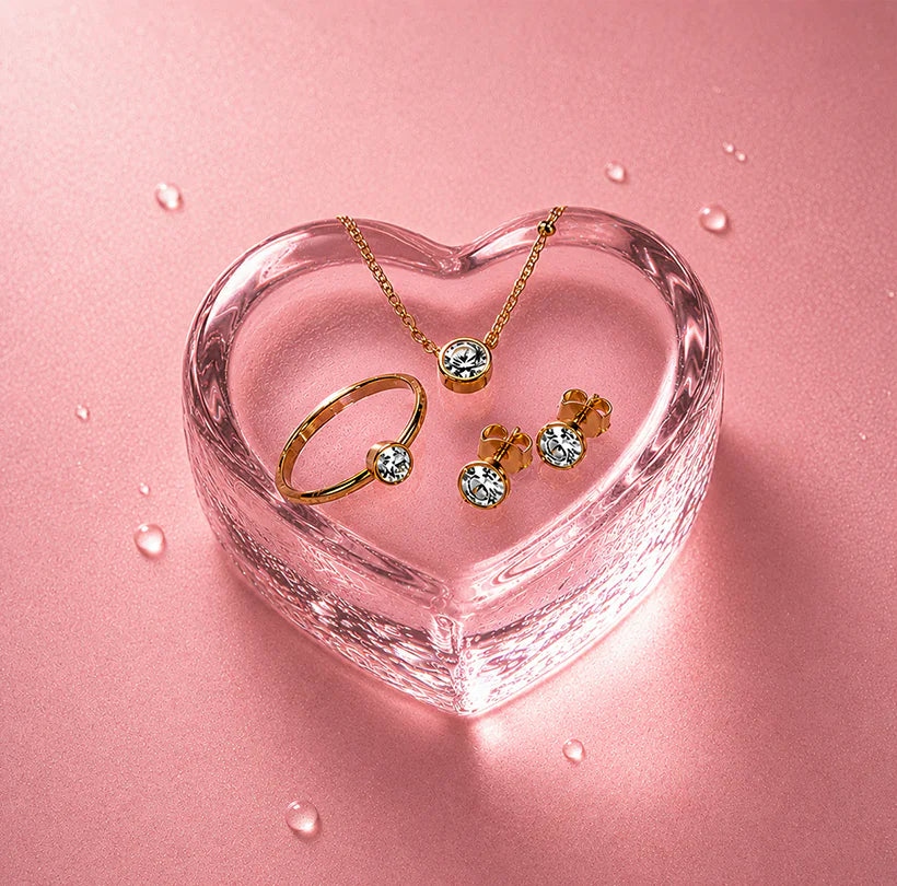 Coordinated gold jewellery set displayed in pink glass